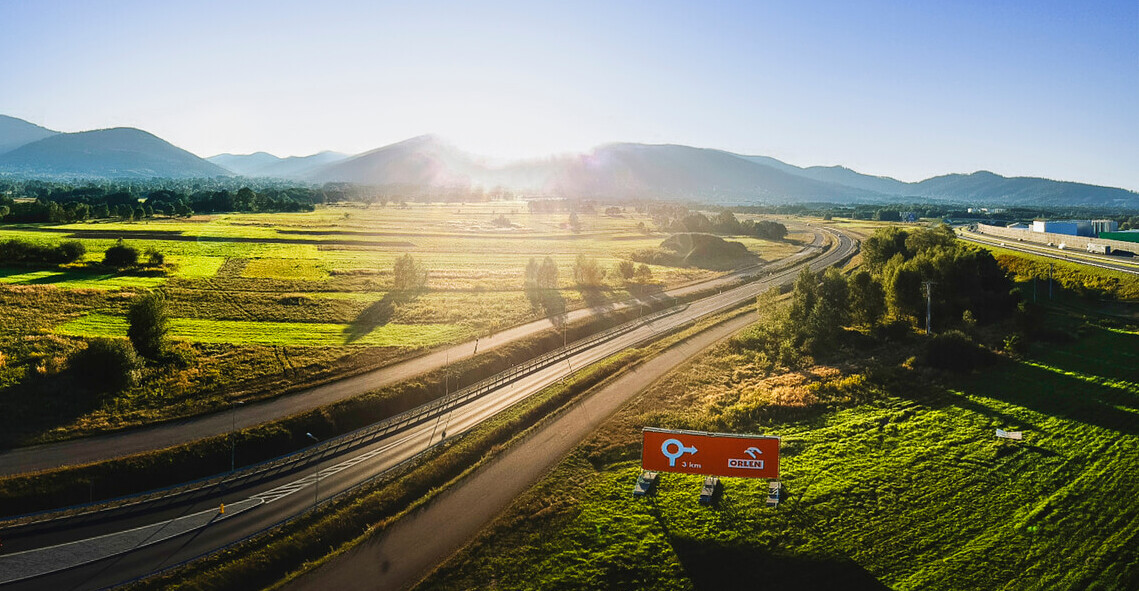 Szerokie ujęcie z drona przedstawiające billboard Orlenu przy drodze.